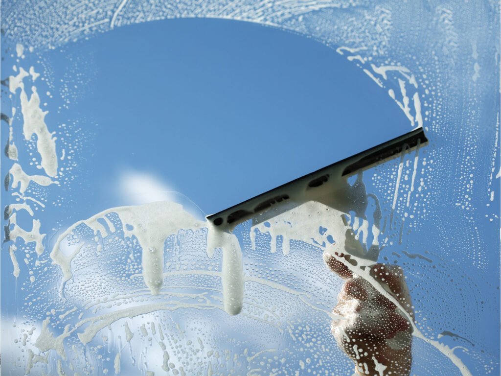 a hand cleaning a window with a squeegee