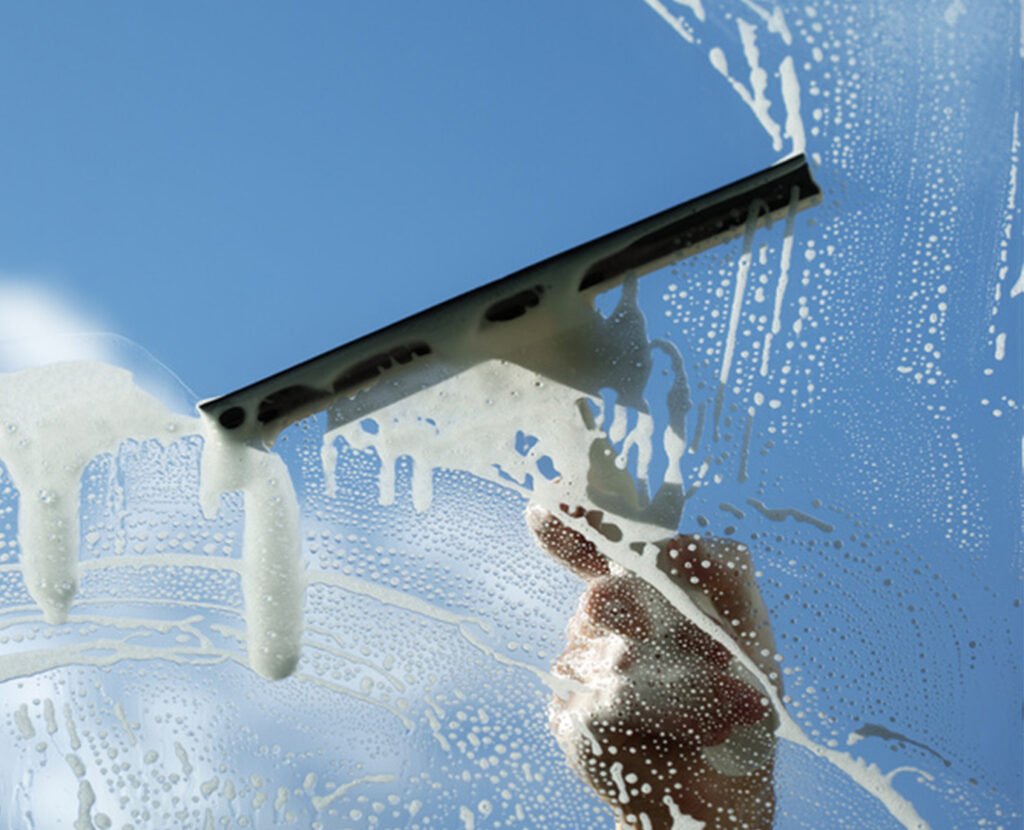 a hand cleaning a window with a squeegee